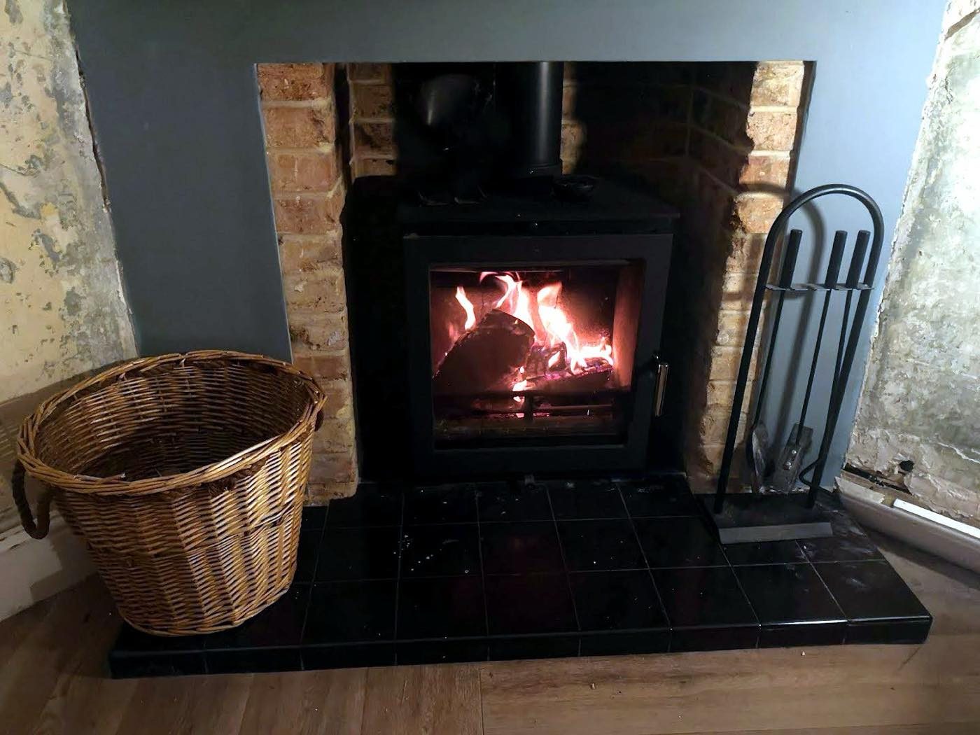 Lit wood burning stove with flames behind the glass door