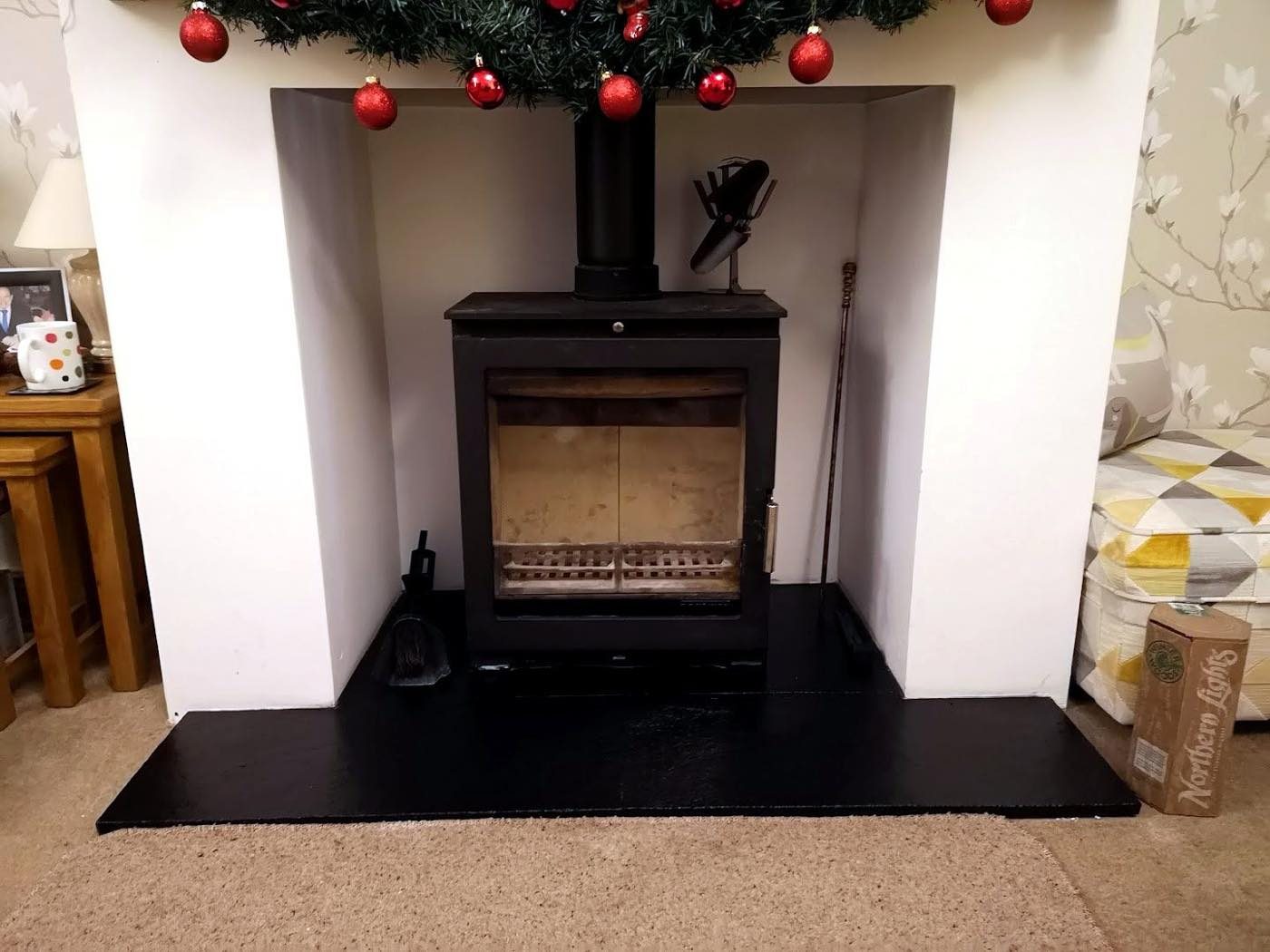 Wood burning stove in a white alcove dressed for Christmas
